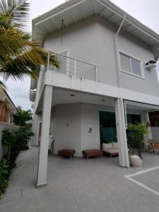 a white house with a balcony and a patio at Casa com piscina 2 Guarujá enseada in Guarujá