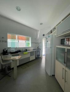a white kitchen with a table and a refrigerator at Casa com piscina 2 Guarujá enseada in Guarujá