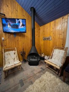 a living room with two chairs and a stove at Charmoso Chalé Hortênsia em Gramado in Gramado