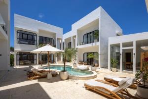 una casa con piscina con sillas y sombrilla en Thomas Beach Apartment, en Uluwatu