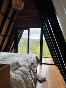 a bed in a room with a large window at Terra Alta Chalé in Gonçalves