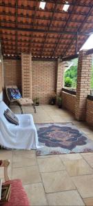 a patio with a bed and a rug on a patio at Recanto dos Passaros centro Penedo RJ in Penedo
