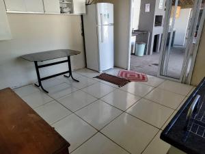 an empty kitchen with a table and a refrigerator at Area de lazer Vale do igapó Bauru in Bauru