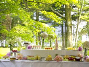 a table with plates of food and vases of flowers at Hotel Karuizawa Elegance in Karuizawa