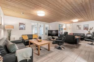 una sala de estar con un sofá y una mesa en Renovated Thatched Pool House By The North Sea For 16 People, en Ulfborg