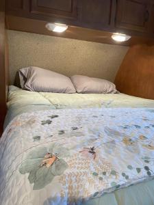 a bed with a floral comforter on it at Cozy Camper in Creal Springs