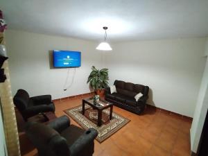 Casa Las Marias في Santa Cruz Muluá: غرفة معيشة مع أرائك وتلفزيون على الحائط
