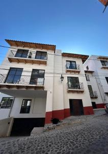 a tall white building with windows and a street at Encanto Taxqueño in Taxco de Alarcón