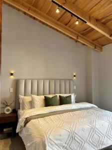 a bedroom with a large white bed and wooden ceilings at Encanto Taxqueño in Taxco de Alarcón