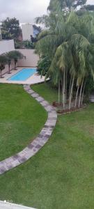 a garden with palm trees and a swimming pool at A melhor acomodação entre Pinhais e Curitiba - quarto para até O4 pessoas em casa com garagem in Curitiba +12 photos
