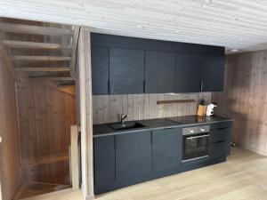 a kitchen with black cabinets and a sink at Kvitfjell Year-round destination-Ski in ski out - World Cup side in Strande