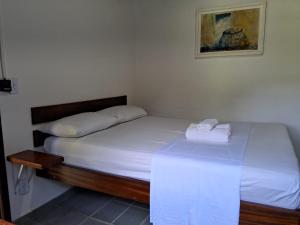 a small bedroom with a bed with white sheets at Sitio Serenar Chalés Equipados in Penedo