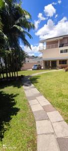 a sidewalk in front of a house with a palm tree at A melhor acomodação entre Pinhais e Curitiba - quarto para até O4 pessoas em casa com garagem in Curitiba