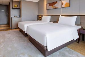 Giường trong phòng chung tại New Century Mansion Hotel Jiaxing Zhongyuan Nanhu Avenue