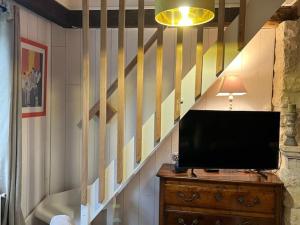 una tv seduta su un comò accanto a una scala di Havre de paix en Berry avec jardin et cheminée - FR-1-591-616 a Brives