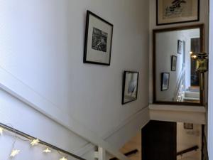 a hallway with a staircase with a mirror and framed pictures at Ferme avec piscine couverte sur grand domaine - FR-1-582-515 in Saint-Romain-Lachalm