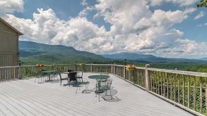 a deck with tables and chairs with mountains in the background at Morning Vista in Gatlinburg