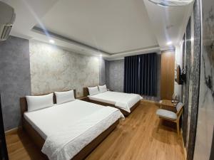 a room with two beds and a chair in it at Thanh Binh Premium Hotel in Ho Chi Minh City