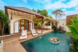 an outdoor pool with chairs and a house at Villa Aldona by Pertama Stay in Tanah Lot