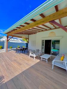 a covered deck with a couch and tables and chairs at La Villa Harmonie in Sainte-Luce