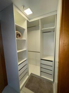 ein begehbarer Kleiderschrank mit weißen Schränken und einer Lampe in der Unterkunft Apartamento charmoso e confortável no DF Century Plaza in Brasilia + 1 Foto