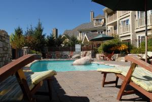 a swimming pool with two chairs and an umbrella at Ermitage du Lac in Mont-Tremblant