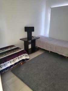 Un dormitorio con una cama y una mesa con una lámpara. en Residencial Las Heras, en Las Heras