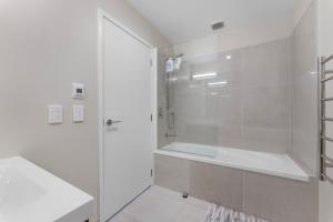 uma casa de banho branca com um chuveiro e uma banheira em New 4BRs Townhouse, Walk to Shops & Cafes, 5mins to Airport, 30mins to Ski em Queenstown