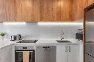 uma cozinha com balcões brancos e armários de madeira em New 4BRs Townhouse, Walk to Shops & Cafes, 5mins to Airport, 30mins to Ski em Queenstown