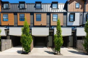 um prédio de apartamentos com árvores em frente em New 4BRs Townhouse, Walk to Shops & Cafes, 5mins to Airport, 30mins to Ski em Queenstown