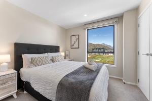 um quarto com uma cama grande e uma janela em New 4BRs Townhouse, Walk to Shops & Cafes, 5mins to Airport, 30mins to Ski em Queenstown