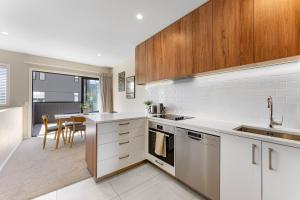 uma cozinha com electrodomésticos brancos e uma mesa com cadeiras em New 4BRs Townhouse, Walk to Shops & Cafes, 5mins to Airport, 30mins to Ski em Queenstown mais 18 fotografias