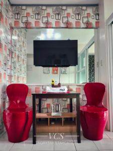 a living room with two red chairs and a table at VCS Tagaytay Staycation in Tagaytay