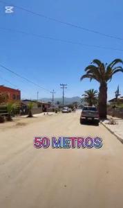 a car parked on a dirt road with a palm tree at Cabañas Armandiños in Pichidangui