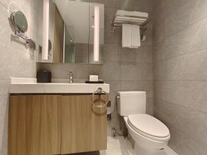 a bathroom with a toilet and a sink and a mirror at Somerset Xuhui Riverside Shanghai serviced apartments in Shanghai
