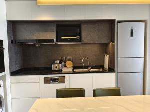 a kitchen with white cabinets and a sink and a refrigerator at Somerset Xuhui Riverside Shanghai serviced apartments in Shanghai