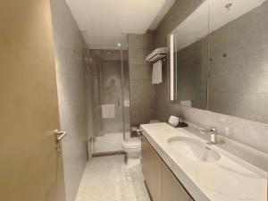 a bathroom with a sink and a toilet and a mirror at Somerset Xuhui Riverside Shanghai serviced apartments in Shanghai