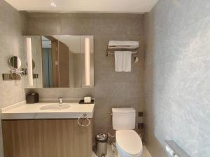 a bathroom with a toilet and a sink and a mirror at Somerset Xuhui Riverside Shanghai serviced apartments in Shanghai