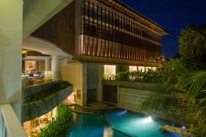 a house with a swimming pool in front of a building at Bali Paragon Resort Hotel in Jimbaran