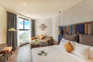 ein Hotelzimmer mit einem großen Bett und einem Stuhl in der Unterkunft Apec Beach Mui Ne Resort in Mui Ne