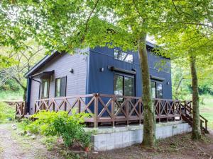 a blue house with a wooden porch in the woods at Guest house KURIHAI - Vacation STAY 21433v in Oita