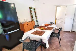 a kitchen with a white table with chairs and a refrigerator at Appartement charmant à Sainte-Rose avec terrasse et jardin – 65 m² in Sainte-Rose
