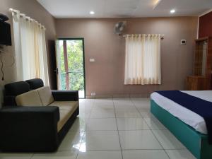 a bedroom with a bed and a couch and a tv at The Rain Tree resort in Kutta
