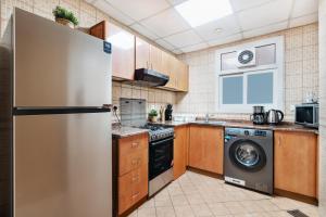 a kitchen with a refrigerator and a dishwasher at Cozy 1 Br Apartment In Axis 2 Residence Dso in Dubai