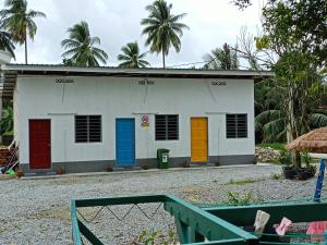 a white building with colorful doors on it at One Mek Bilik Queen in Kampong Jelutong