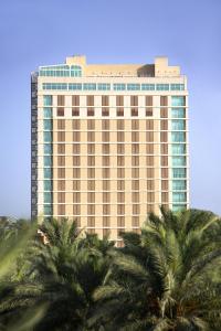 a tall building with palm trees in front of it at Karbala Rayhaan Hotel & Suites in Karbala