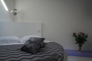 ein Schlafzimmer mit einem Bett mit einem Kissen und einer Vase aus Blumen in der Unterkunft Ca' Ottocento in Lazise