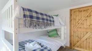 ein Schlafzimmer mit einem Etagenbett und einer Holztür in der Unterkunft Beach Breeze Cottage - 3 Bed in Caister-on-Sea