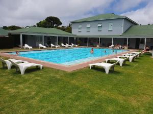 a large swimming pool with chairs and people in it at 4250 River Club in Plettenberg Bay