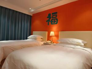 two beds in a room with an orange wall at 福禄寿酒店 in Beiwusidui